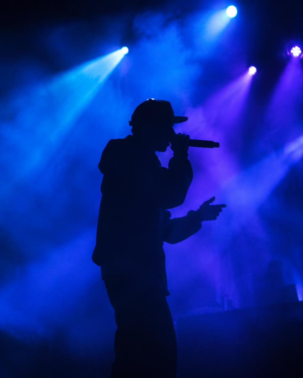 Artista em palco com luzes azuis e roxas